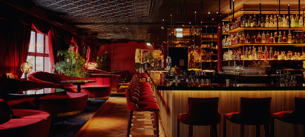 Provocateur Berlin Bar: Große Bar über Eck, bequeme Sitznischen aus rotem Samt, gemütliches gedimmtes Licht
