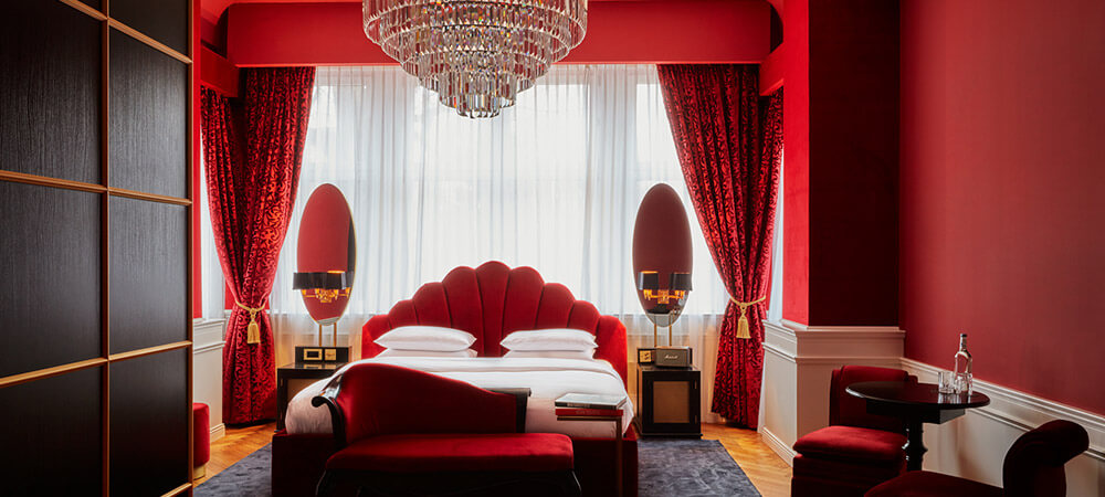 Deluxe Room: schwere rote Samtvorhänge, bequeme Sitzgelegenheiten und warmes Licht