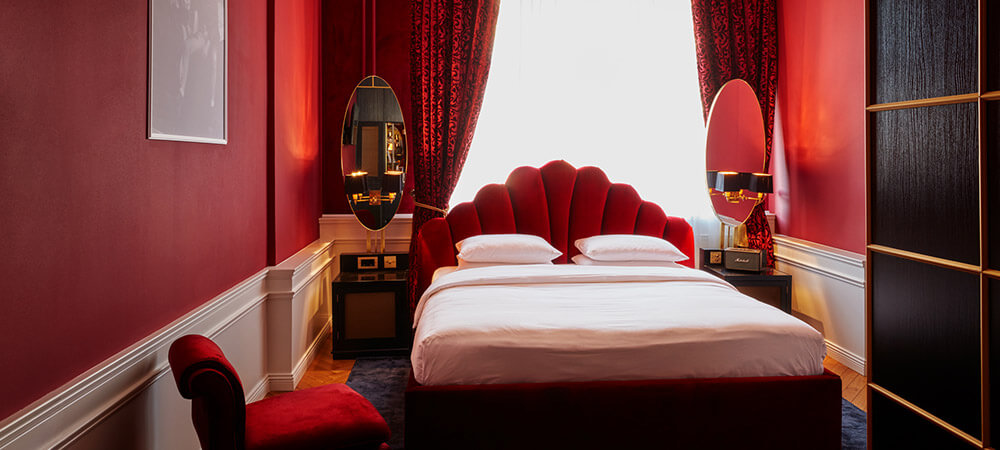 Superior Room: Schwarzer Holzwandschrank, prunkvolles Bett in rotem Zimmer mit großen Spiegeln neben dem Bett