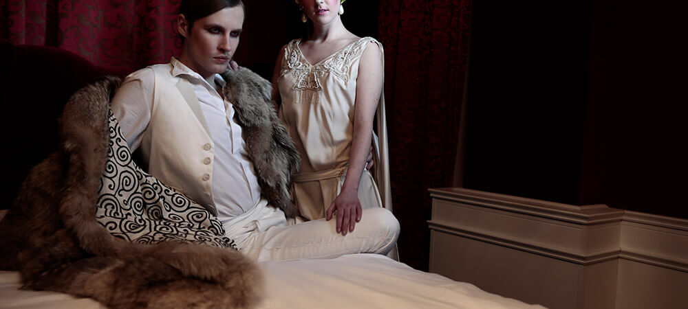 Provocateur Berlin, Paar posiert auf Bett, gekleidet im 20er Jahre Style